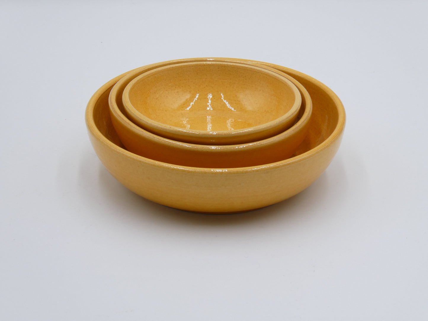 Set of three yellow ceramic bowls in 3 different sizes that can be stacked inside each other.